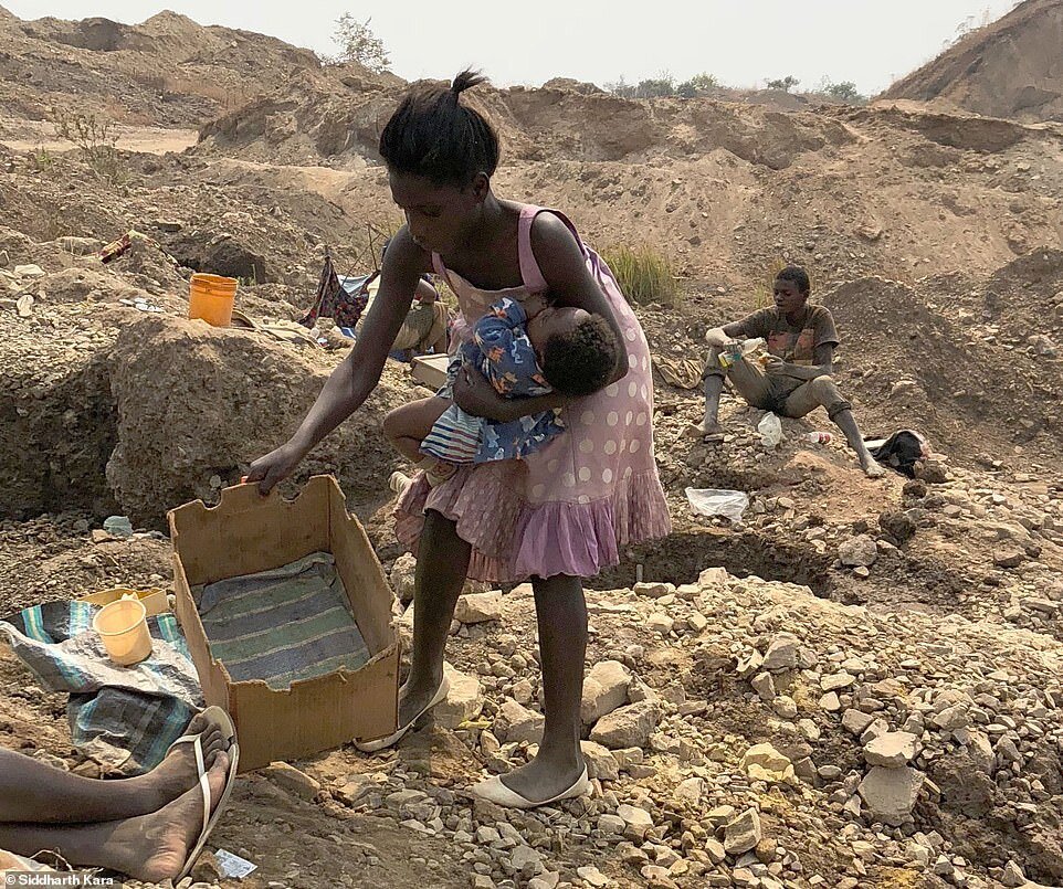 66883379-11668015-A_woman_carries_her_infant_as_she_mines_for_cobalt_in_the_hills_-a-1_1675084854755